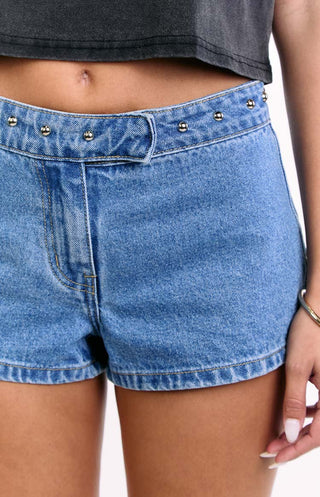 Pantalones cortos vaqueros Mollie de mezclilla de lavado medio y talle bajo con tachuelas.